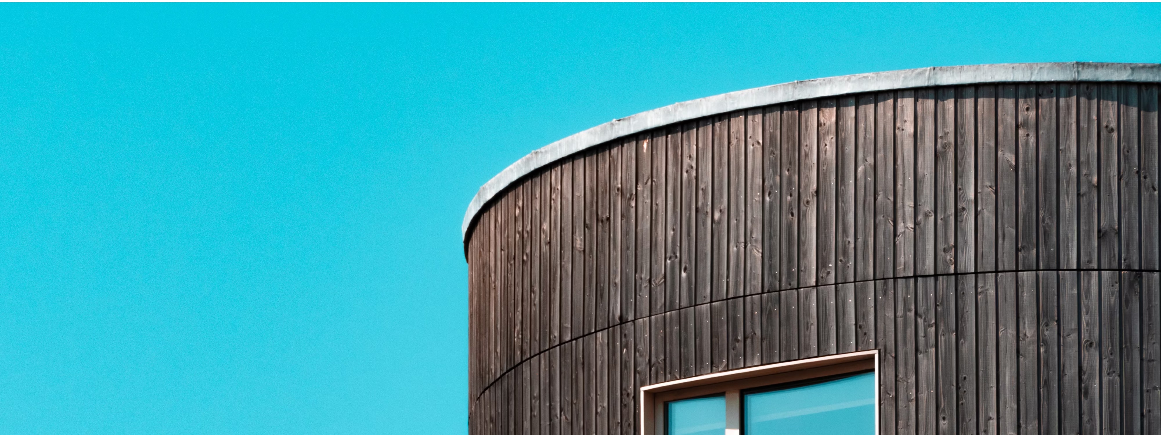Curved wooden building with window against bright turquoise background